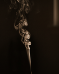A thread of incense smoke curling against a dark ground
